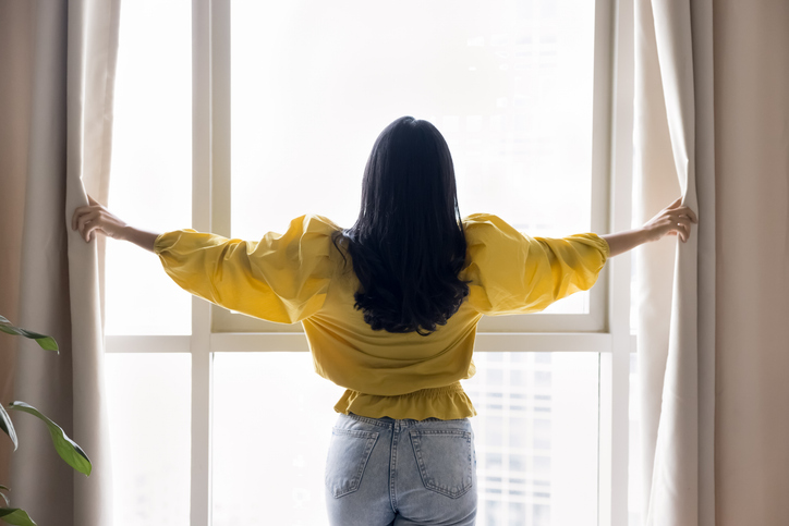 Woman opening curtains at window